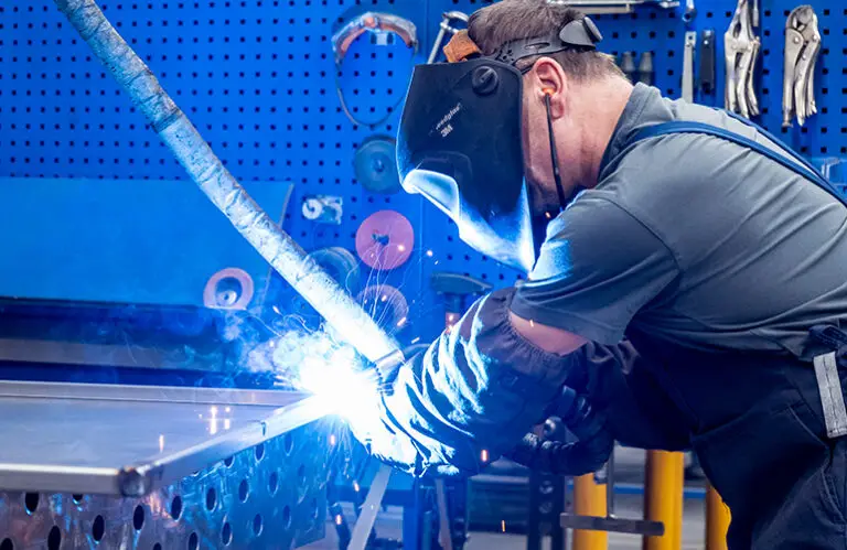 A welder is fabricating a steel welded assembly - precision manual welding in mechanical engineering.