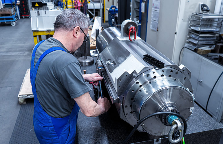 An employee is assembling a spindle assembly. The spindle is aligned with precision and inspected.